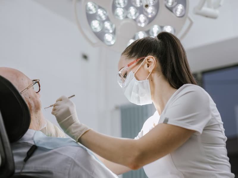 Dentista atendendo um paciente na cadeira, sob o foco de luz