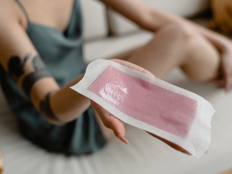 Aplicação de faixa de cera na perna de uma cliente