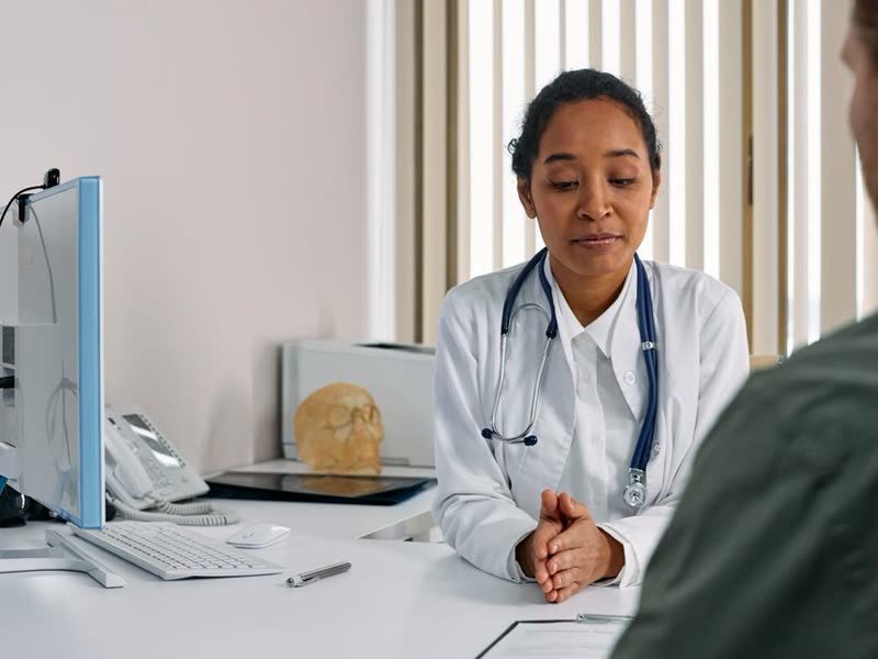 Médica com estetoscópio atendendo um paciente na mesa do consultório