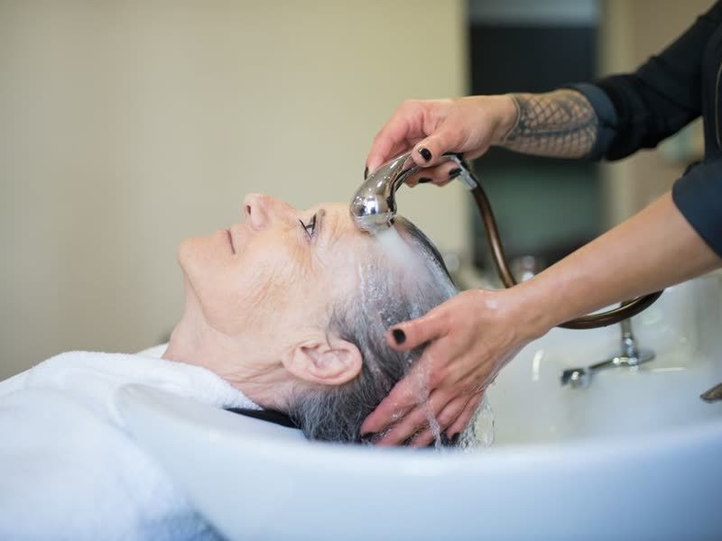 Cabeleireira lavando o cabelo de uma cliente na cuba do salão